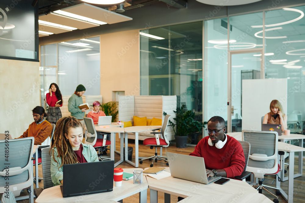 Young serious office managers or designers of various ethnicities using laptops Young serious office managers or designers of various ethnicities using laptops