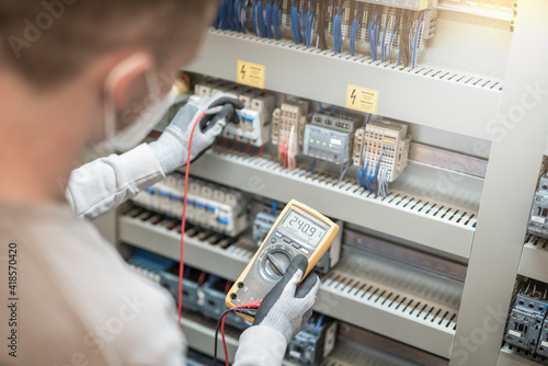 Electricians hands testing current electric in control panel
