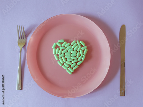 green tablets, vitamins in form of heart on the plate on colorful background. Health care, treatment, food, cure concept photo