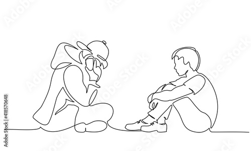 Two young boys teenagers sitting together and one talking by phone.