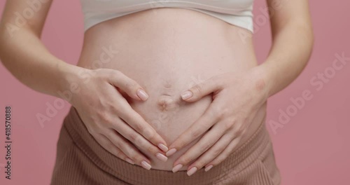 Wallpaper Mural Pure mothers love. Close up of pregnant woman embracing her big belly, pink studio background, slow motion Torontodigital.ca