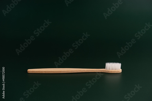 Eco friendly dental health antibacterial bamboo wood toothbrush on dark green background