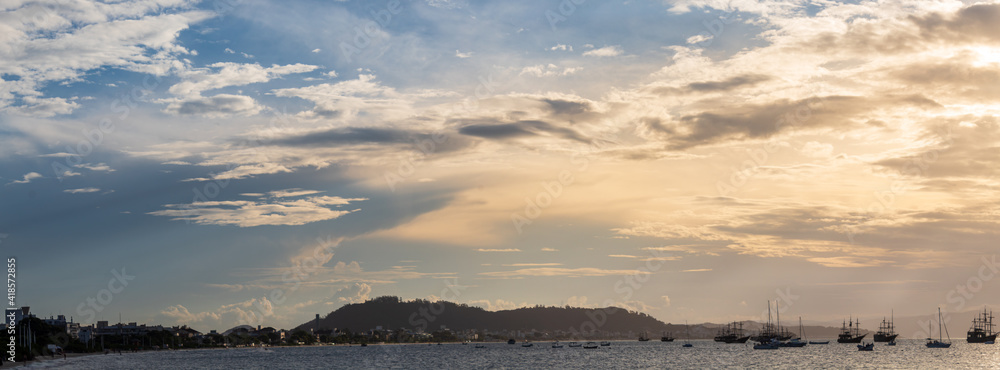 Fototapeta premium panoramic of the Sunset on a tropical beach with pirate boats in the background, located on the beach of Cachoeira do Bom Jesus, Canasvieras, Ponta das Canas, Florianópolis, Santa Catarina, Brazil