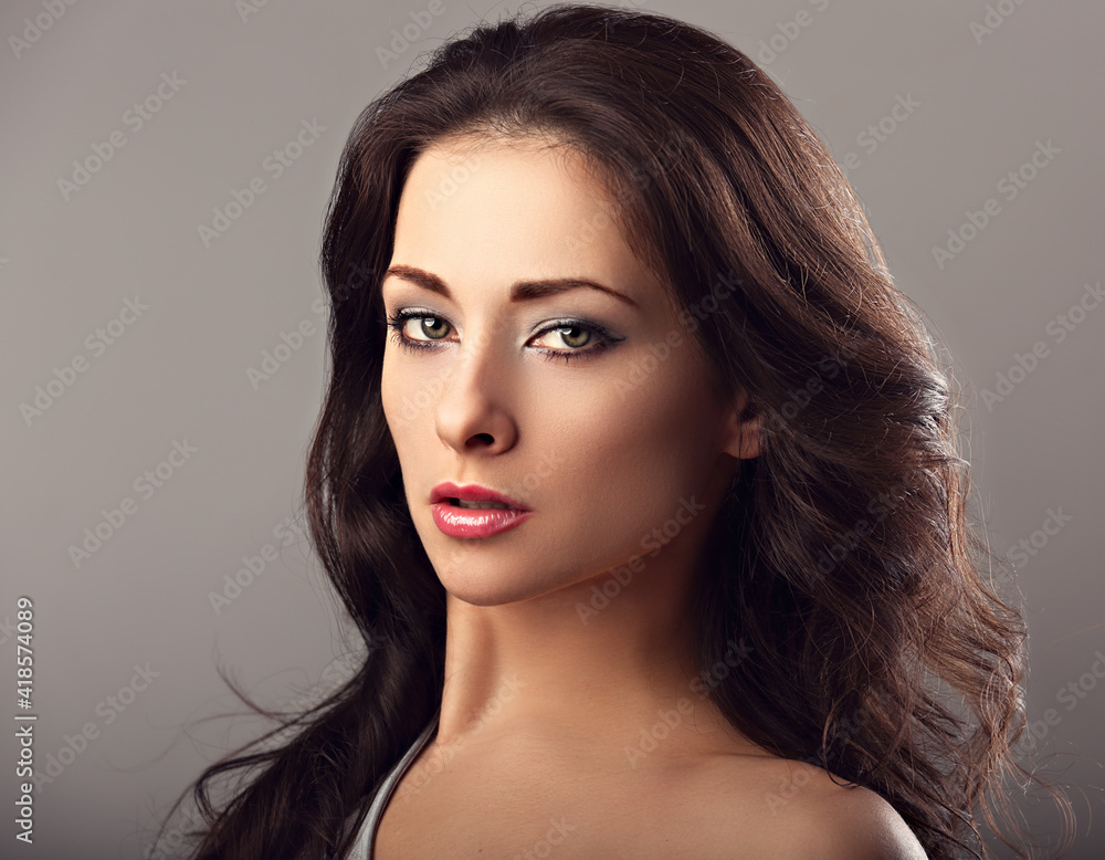 Beautiful mysterious woman makeup face and healthy volume brown hair with wisdom emotional look on brown color background with empty copy space. Closeup Beautiful mysterious woman makeup face and healthy volume brown hair with wisdom emotional look on brown color background with empty copy space. Closeup