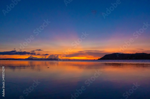 Wonderful sunset landscape on the seashore, colors of the sunset sky and silhouette of island in the water. incredible tropical sunset