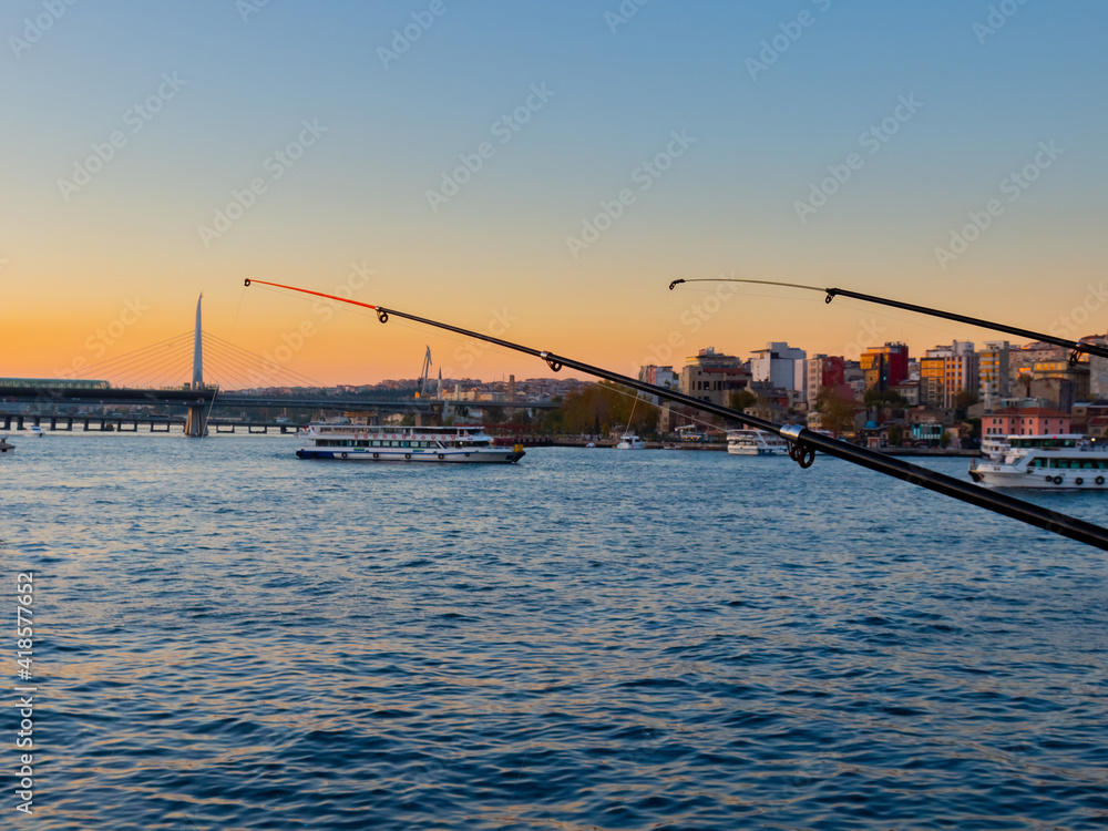 Fototapeta premium Fishing rods at sunset on Galata Bridge in Istanbul, Turkey. Popular hobby and relaxing.