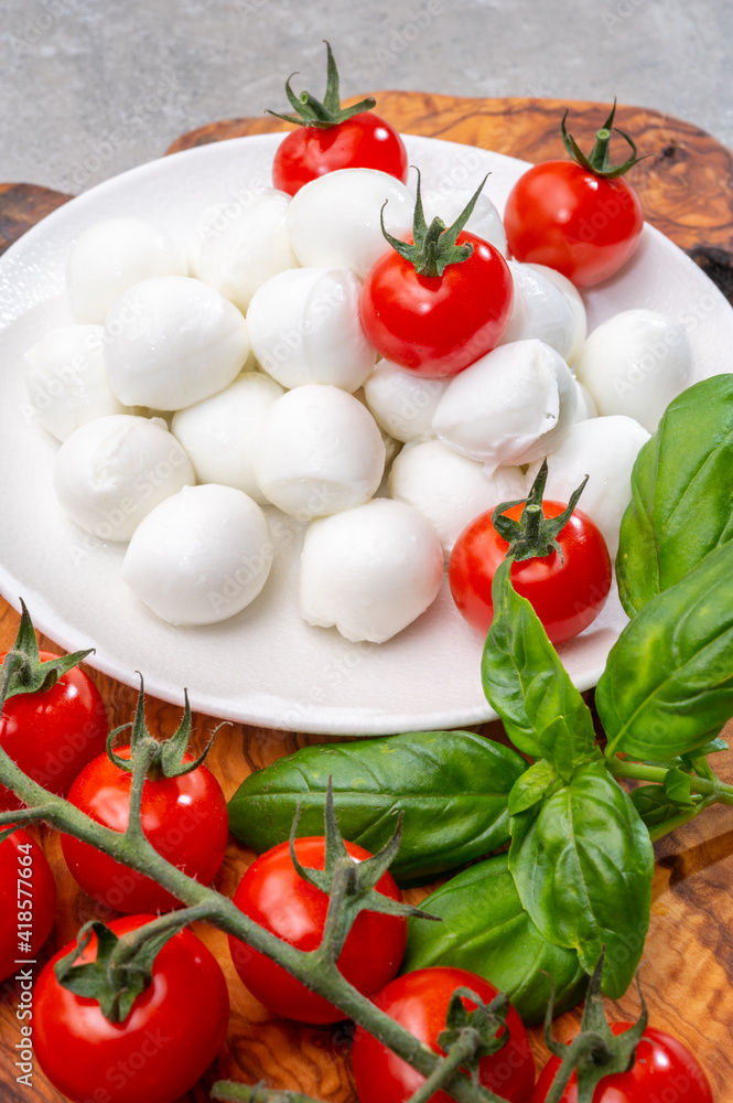 Italian tricolore, small balls of fresh white soft Italian mozzarella cheese, ripe red cherry tomatoes and fresh green basil herb, ready for making caprese salad Italian tricolore, small balls of fresh white soft Italian mozzarella cheese, ripe red cherry tomatoes and fresh green basil herb, ready for making caprese salad