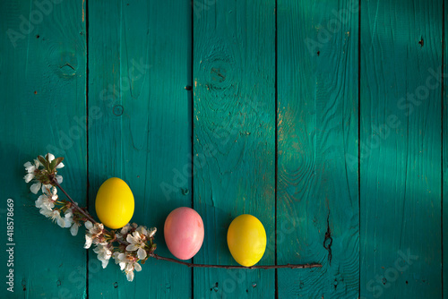 Easter, holidays and tradition concept. Colorful Easter eggs painted in pastel colors on wooden boards background with blossom cherry.