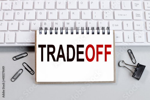 TRADE-OFF. text on white notepad paper on white keyboard photo