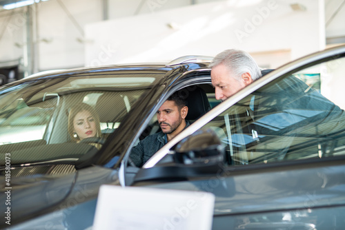 Young family talking to the salesman and choosing their new car in a showroom