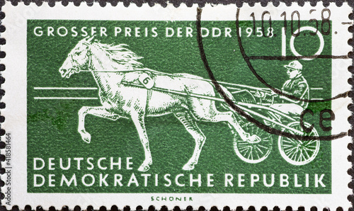 GERMANY  DDR - CIRCA 1958   a postage stamp from Germany  GDR showing a team of horses at a trotting race. Text  Horse racing Grand Prix of the GDR