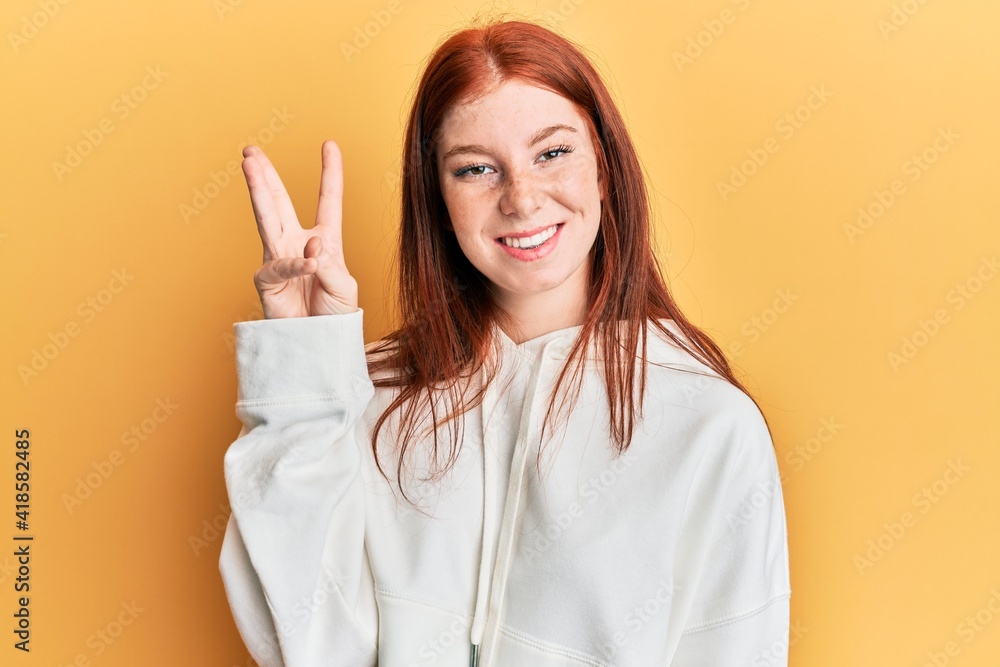 Young red head girl wearing casual sweatshirt showing and pointing up with fingers number three while smiling confident and happy. Young red head girl wearing casual sweatshirt showing and pointing up with fingers number three while smiling confident and happy.