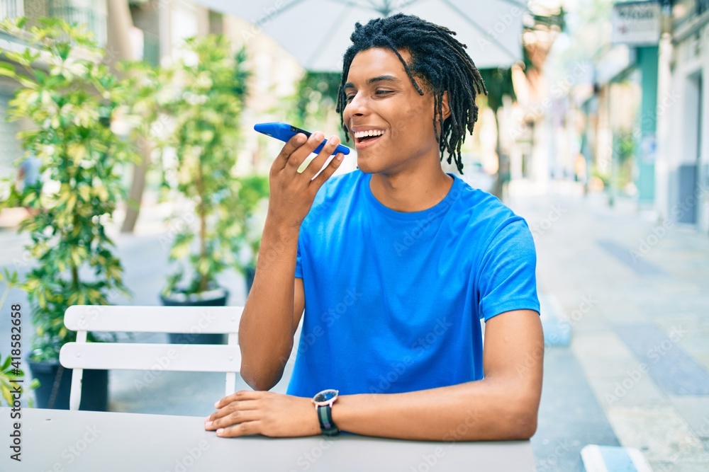 Young african american man smiling happy sending audio message using smartphone at terrace..
