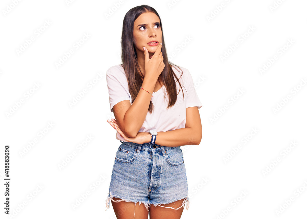 Young hispanic woman wearing casual white tshirt thinking worried about a question, concerned and nervous with hand on chin Young hispanic woman wearing casual white tshirt thinking worried about a question, concerned and nervous with hand on chin