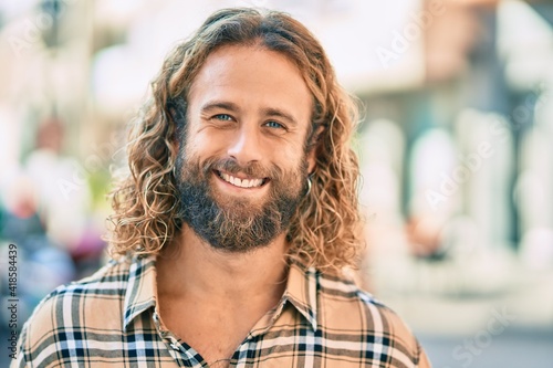 Young caucasian man with long hair smiling happy at the city.