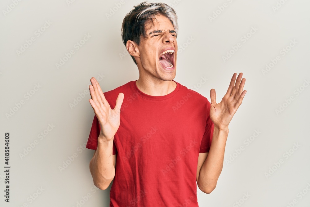 Young hispanic man wearing casual clothes celebrating mad and crazy for success with arms raised and closed eyes screaming excited. winner concept Young hispanic man wearing casual clothes celebrating mad and crazy for success with arms raised and closed eyes screaming excited. winner concept