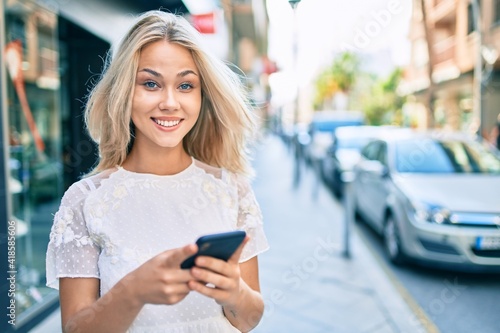 Young caucasian girl smiling happy using smartphone at street of city.