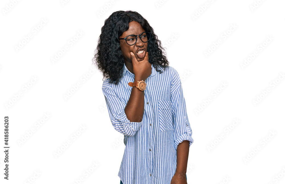 Beautiful african young woman wearing casual clothes and glasses thinking worried about a question, concerned and nervous with hand on chin Beautiful african young woman wearing casual clothes and glasses thinking worried about a question, concerned and nervous with hand on chin