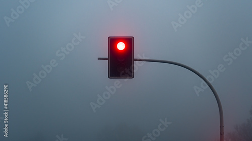 Red stop light on foggy mystical morning.