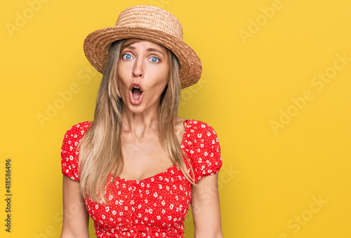 Beautiful caucasian woman wearing summer hat afraid and shocked with surprise expression, fear and excited face.