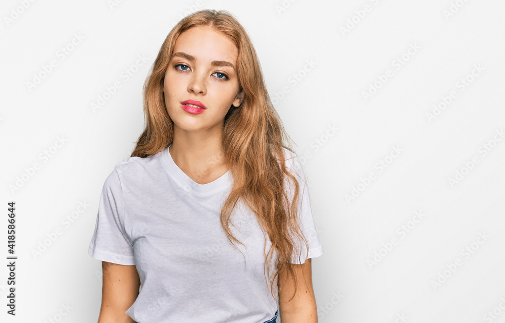 Young caucasian girl wearing casual white t shirt with serious expression on face. simple and natural looking at the camera. Young caucasian girl wearing casual white t shirt with serious expression on face. simple and natural looking at the camera.