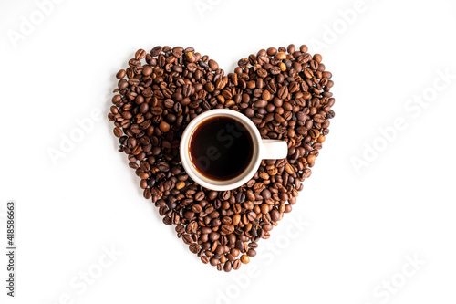 A break for coffee lovers. A cup of coffee inside a heart made of coffee beans. Flat lay composition on a white background.