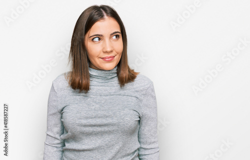 Young beautiful woman wearing casual turtleneck sweater smiling looking to the side and staring away thinking.