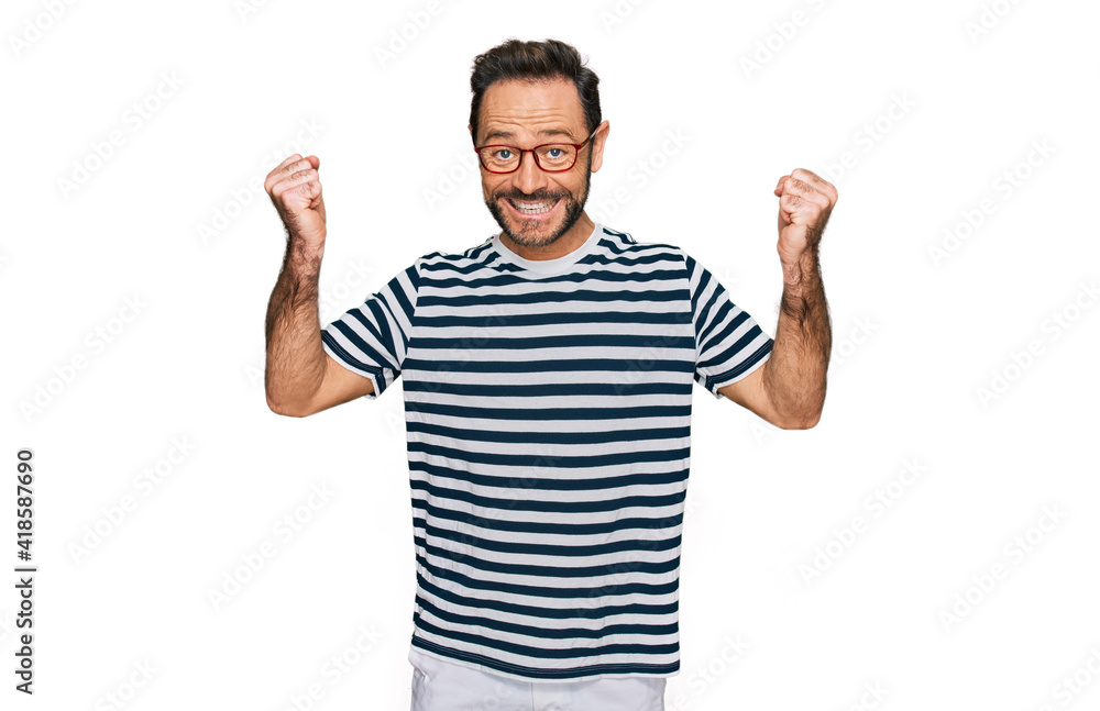 Middle age man wearing casual clothes and glasses celebrating surprised and amazed for success with arms raised and open eyes. winner concept. Middle age man wearing casual clothes and glasses celebrating surprised and amazed for success with arms raised and open eyes. winner concept.