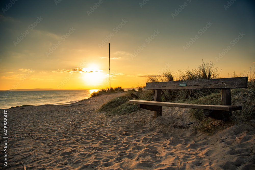 bench on the beach with sunset