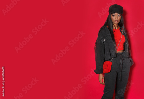 Professional fashion model posing in studio on red background.