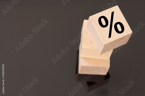 Percent sign on wooden cubes against black background. Concept of sale and discount.