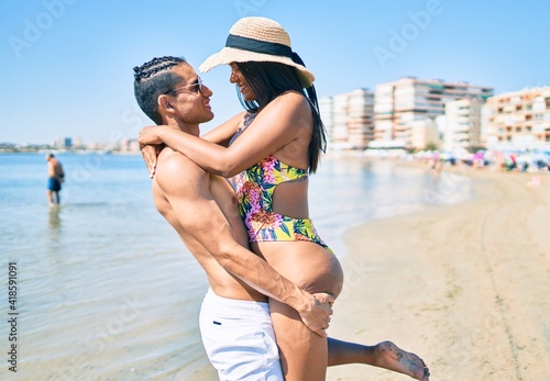 Young latin couple wearing swimwear  smiling happy walking at the beach. © Krakenimages.com