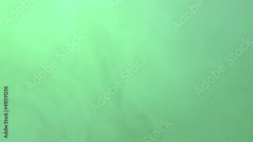 Dark ink spreading in green-blue water. Abstract color background, liquid smoke effect, psychedelic and art concept.