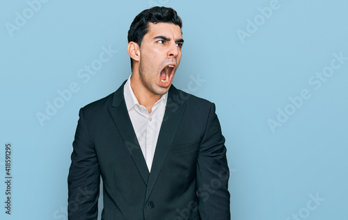 Handsome hispanic man wearing business clothes angry and mad screaming frustrated and furious, shouting with anger. rage and aggressive concept.