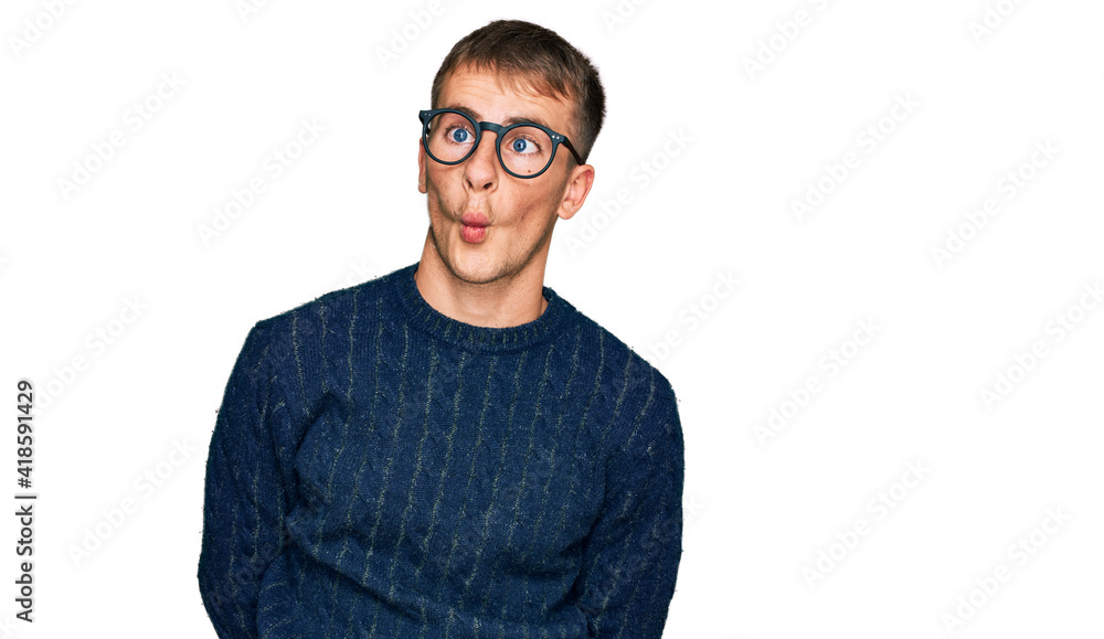 Young blond man wearing casual clothes and glasses making fish face with lips, crazy and comical gesture. funny expression. Young blond man wearing casual clothes and glasses making fish face with lips, crazy and comical gesture. funny expression.