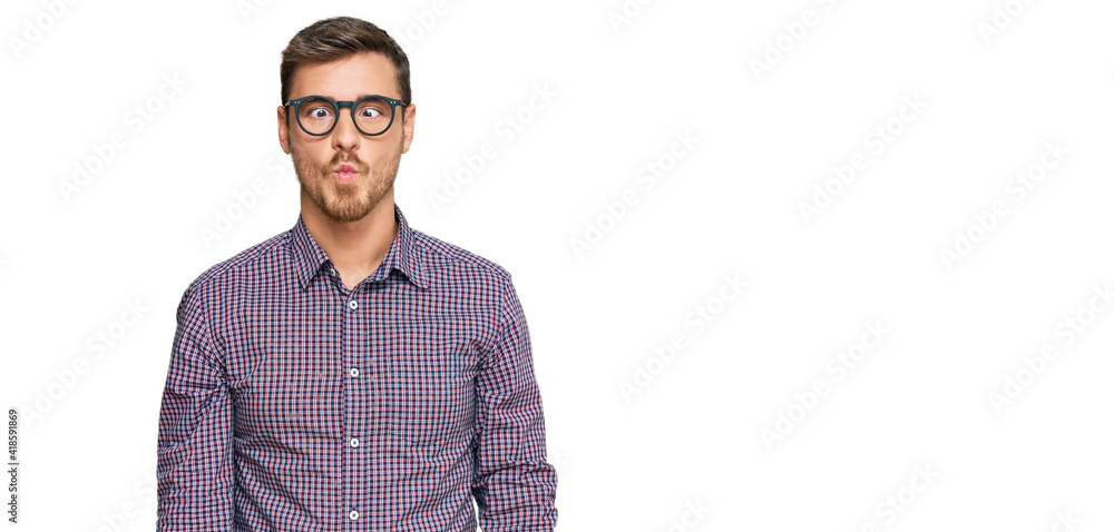Handsome caucasian man wearing casual clothes and glasses making fish face with lips, crazy and comical gesture. funny expression. Handsome caucasian man wearing casual clothes and glasses making fish face with lips, crazy and comical gesture. funny expression.