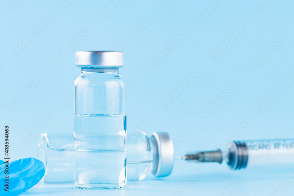 Vaccine, syringe and surgical glove. Two bottles of vaccine and syringe on a blue background. Vaccine and healthcare medical concept Vaccine, syringe and surgical glove. Two bottles of vaccine and syringe on a blue background. Vaccine and healthcare medical concept