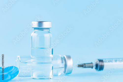 Vaccine, syringe and surgical glove. Two bottles of vaccine and syringe on a blue background. Vaccine and healthcare medical concept