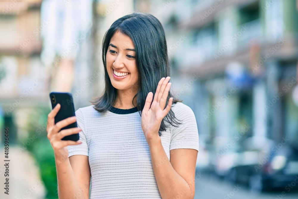 Young hispanic woman smiling happy doing video call using smartphone at the city.
