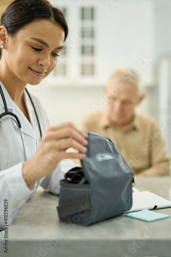 Amicable woman in white labcoat opening a bag with manometer