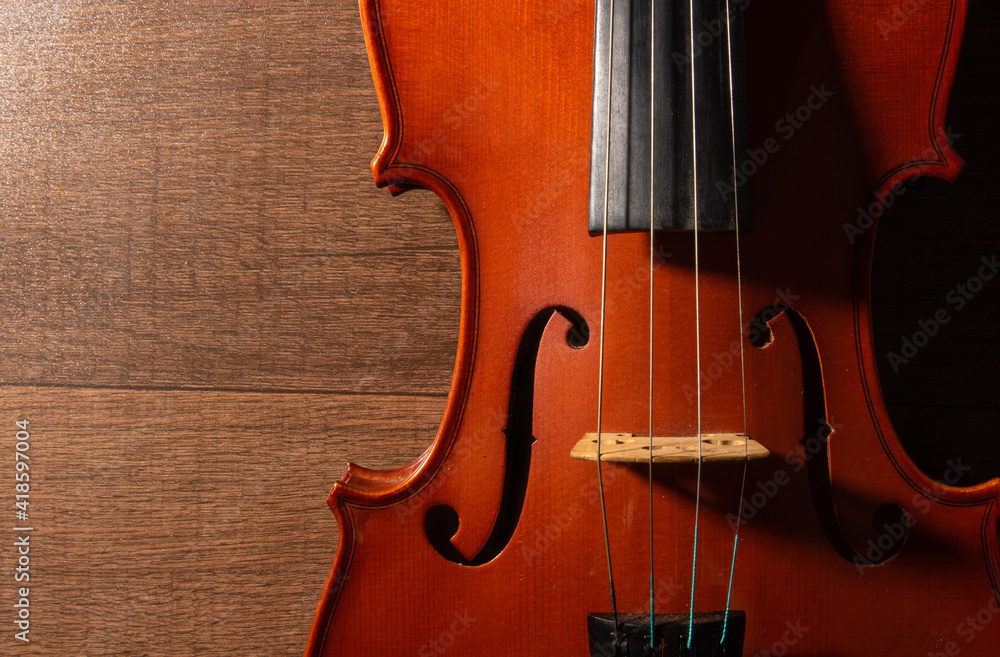 Violin, details of a beautiful violin on wooden surface and black background, low key selective focus portrait. Violin, details of a beautiful violin on wooden surface and black background, low key selective focus portrait.