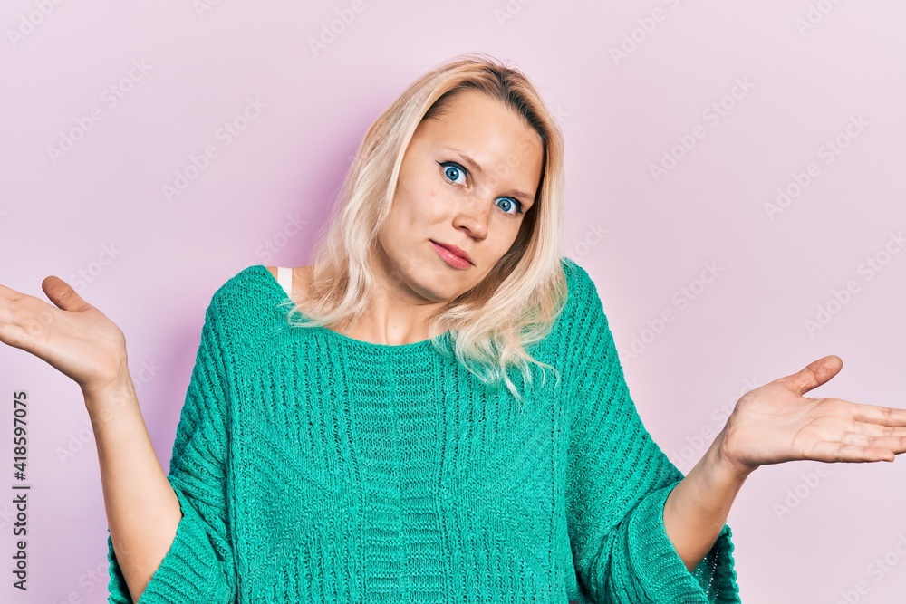 Beautiful caucasian blonde woman wearing casual winter sweater clueless and confused with open arms, no idea and doubtful face. Beautiful caucasian blonde woman wearing casual winter sweater clueless and confused with open arms, no idea and doubtful face.