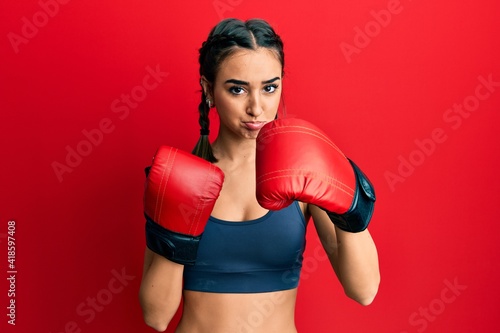 Young brunette girl using boxing gloves depressed and worry for distress, crying angry and afraid. sad expression. © Krakenimages.com