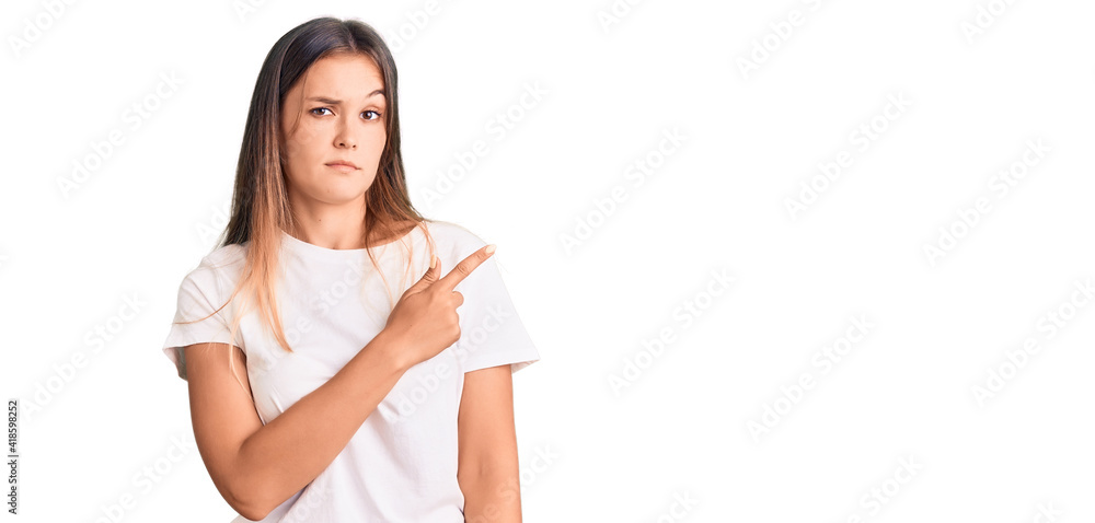 Beautiful caucasian woman wearing casual white tshirt pointing with hand finger to the side showing advertisement, serious and calm face Beautiful caucasian woman wearing casual white tshirt pointing with hand finger to the side showing advertisement, serious and calm face