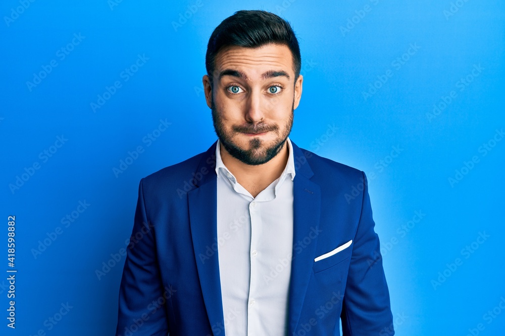 Young hispanic businessman wearing business jacket puffing cheeks with funny face. mouth inflated with air, crazy expression. Young hispanic businessman wearing business jacket puffing cheeks with funny face. mouth inflated with air, crazy expression.