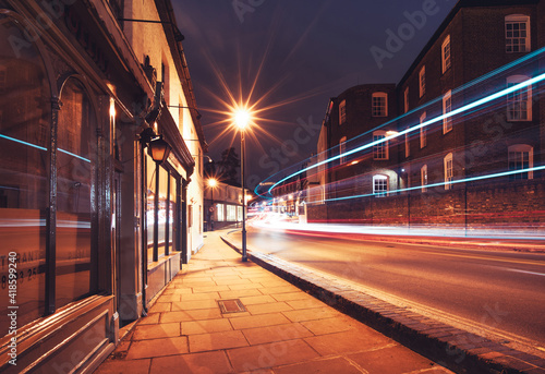 Canvas Print Harrow on the Hill by night with passing cars and buses in motion, England