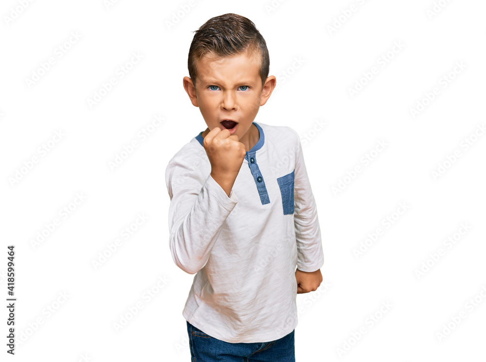 Adorable caucasian kid wearing casual clothes angry and mad raising fist frustrated and furious while shouting with anger. rage and aggressive concept. Adorable caucasian kid wearing casual clothes angry and mad raising fist frustrated and furious while shouting with anger. rage and aggressive concept.