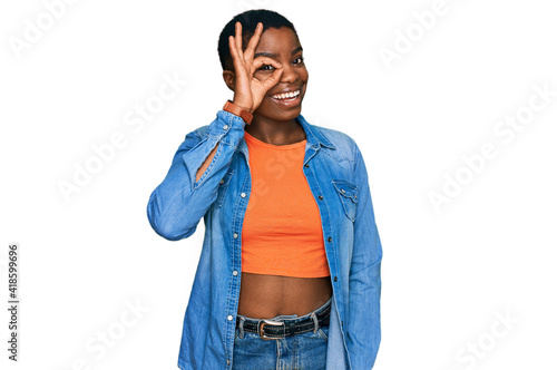 Young african american woman wearing casual clothes doing ok gesture with hand smiling, eye looking through fingers with happy face.