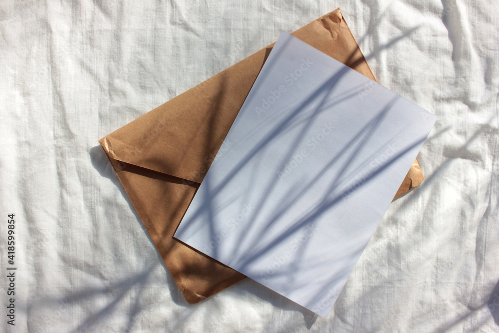 Brown kraft envelope and white blank paper card on bed crumpled texture