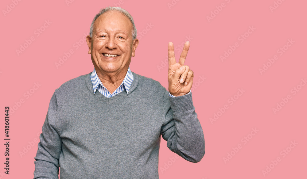 Senior caucasian man wearing casual clothes smiling with happy face winking at the camera doing victory sign. number two. - obrazy, fototapety, plakaty 